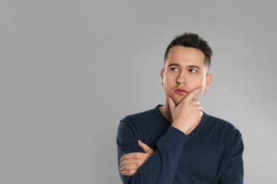 Photo of Portrait of thoughtful young man on grey background. Space for text