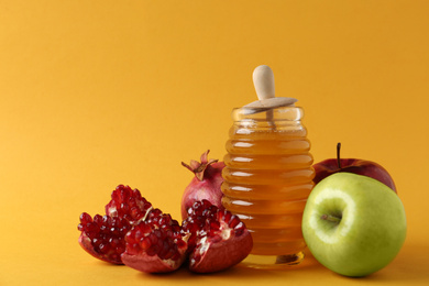 Photo of Honey, apples and pomegranate on orange background. Rosh Hashanah holiday