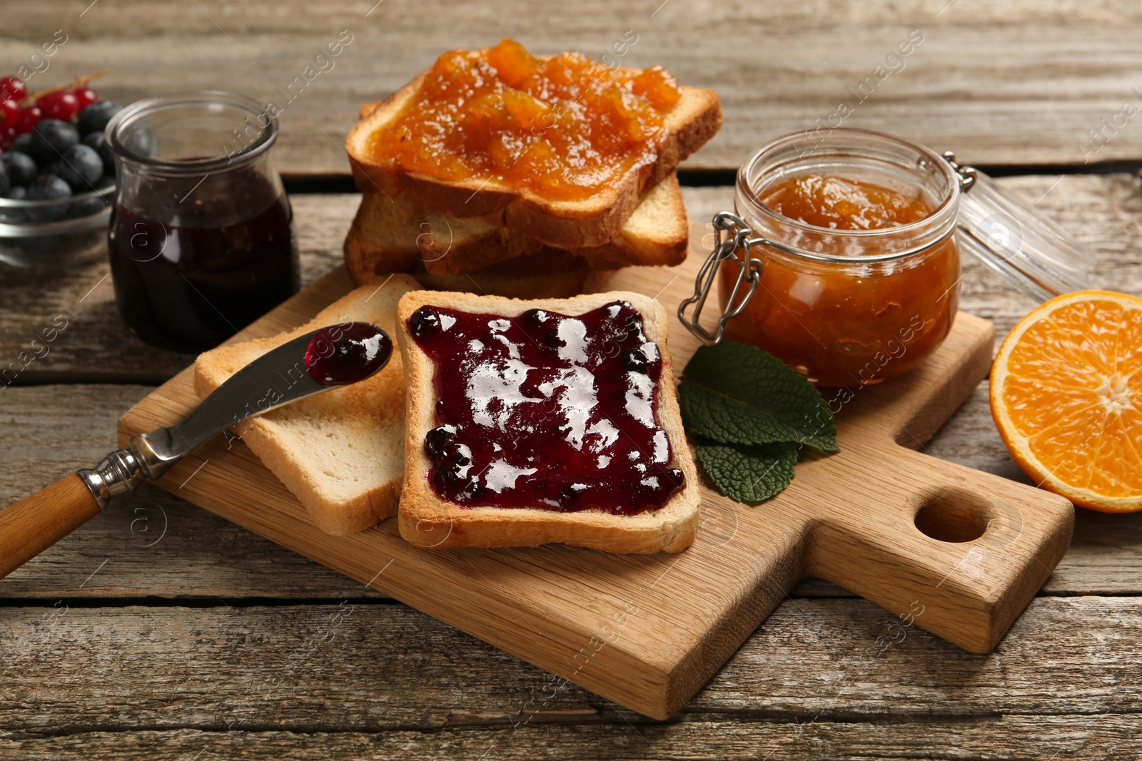 Photo of Delicious toasts served with jams and fruits on wooden table