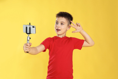 Photo of Cute little blogger recording video on yellow background