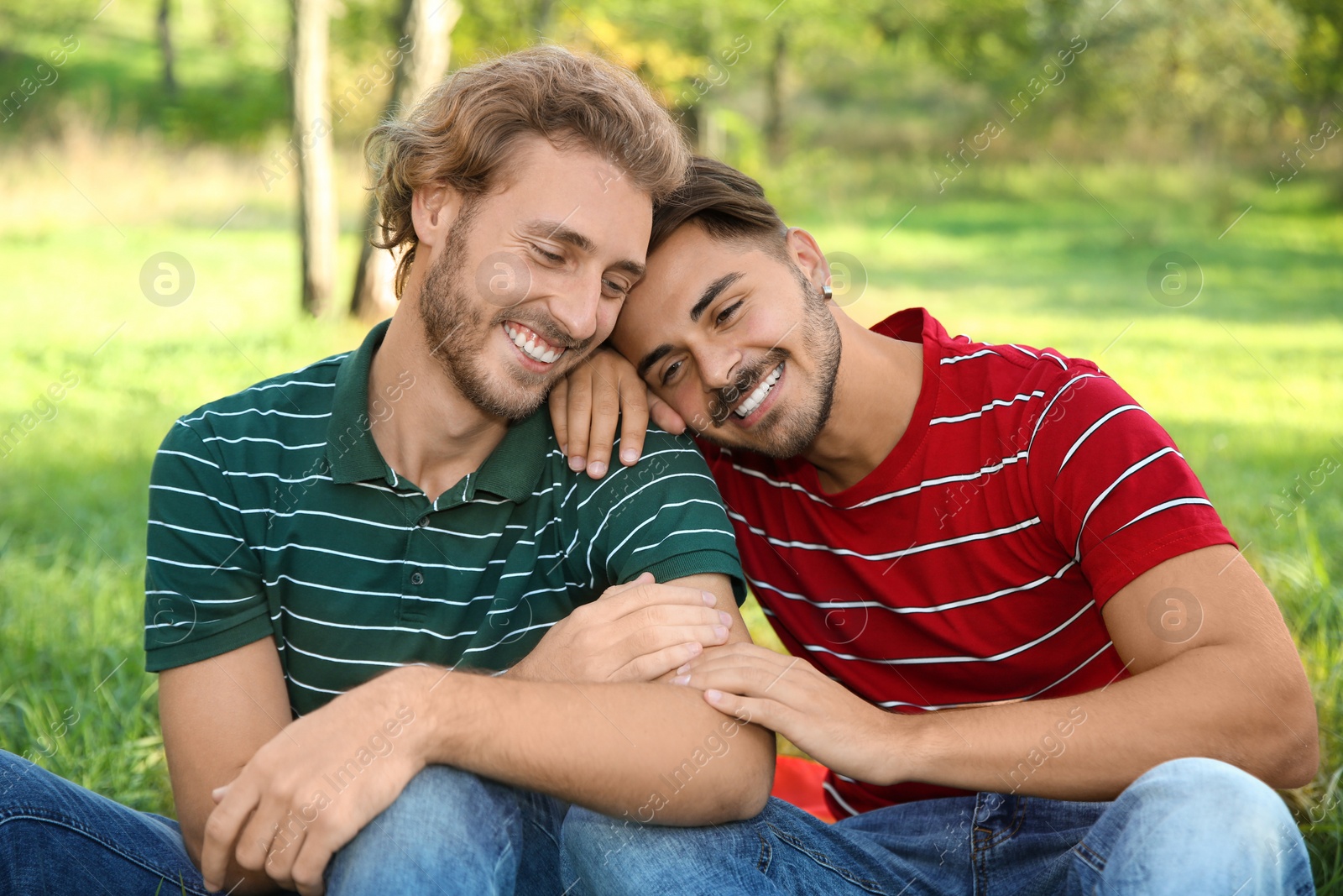 Photo of Portrait of happy gay couple smiling in park