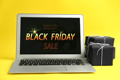 Photo of Laptop with Black Friday announcement and gifts on yellow background
