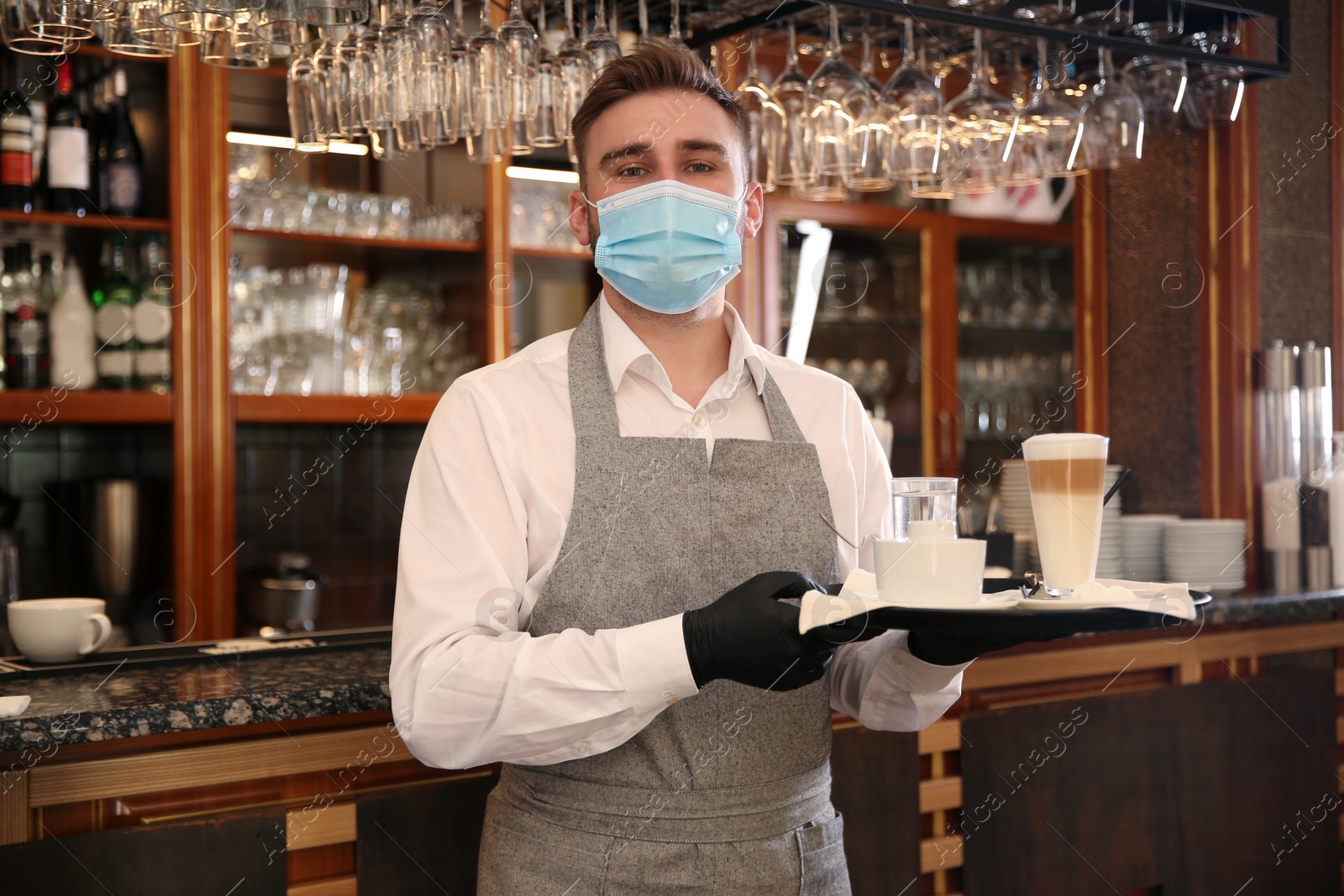 Photo of Waiter holding tray with beverages in restaurant. Catering during coronavirus quarantine