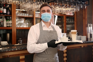 Photo of Waiter holding tray with beverages in restaurant. Catering during coronavirus quarantine