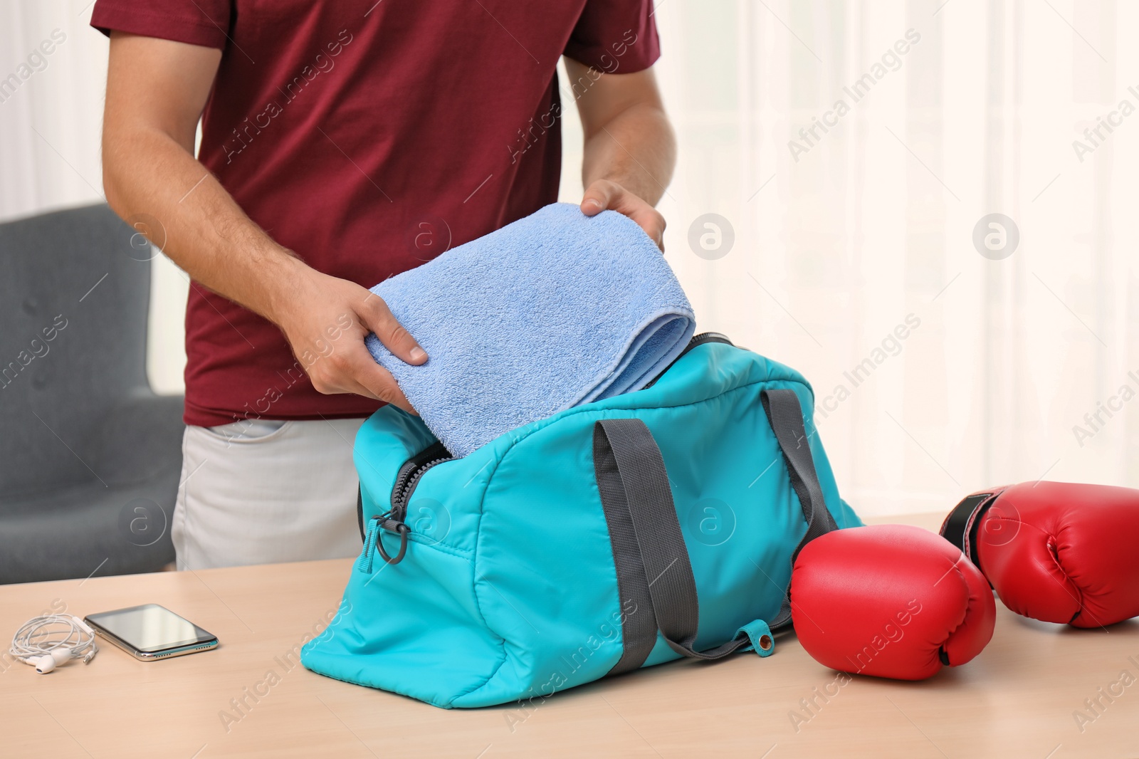 Photo of Young man packing sports bag on table