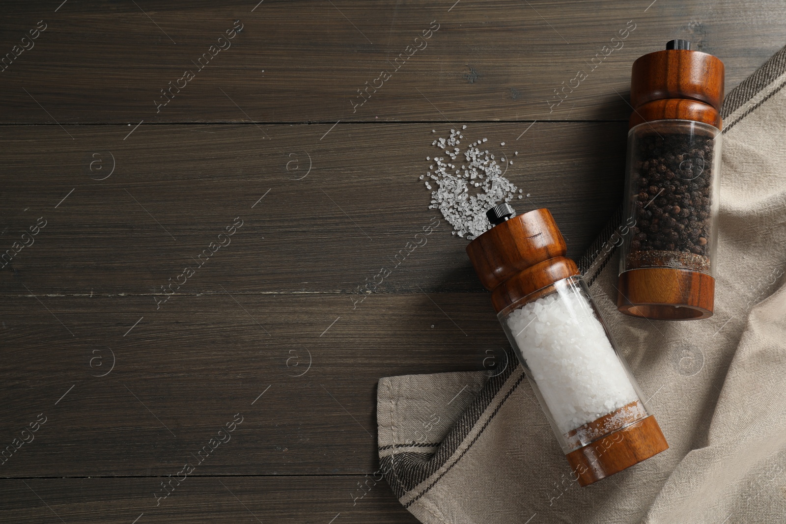 Photo of Salt and pepper shakers on wooden table, flat lay. Space for text