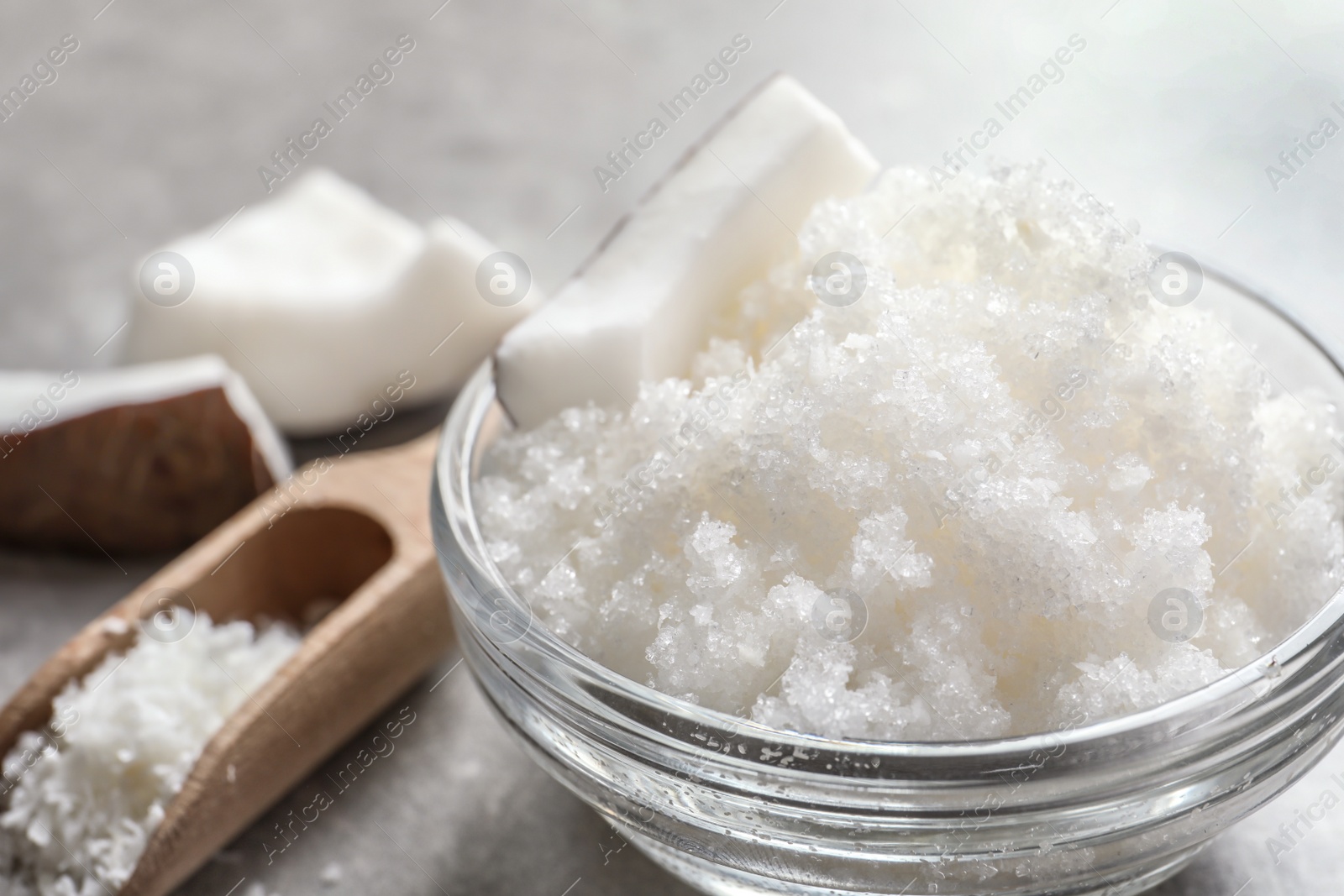 Photo of Glass bowl with natural coconut scrub on table, closeup