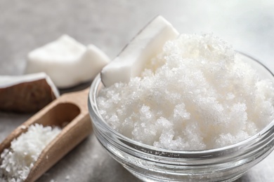 Glass bowl with natural coconut scrub on table, closeup