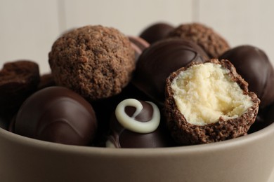 Photo of Many different delicious chocolate truffles in bowl, closeup