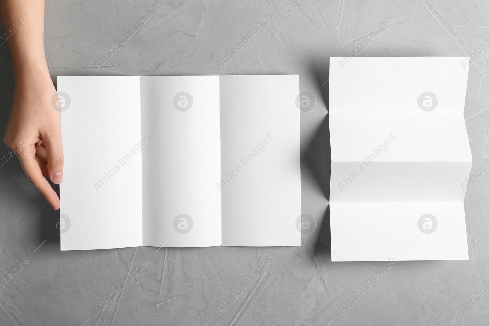 Photo of Woman with blank brochures on grey background, top view. Mockup for design