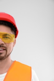 Photo of Male industrial engineer in uniform on light background, space for text. Safety equipment