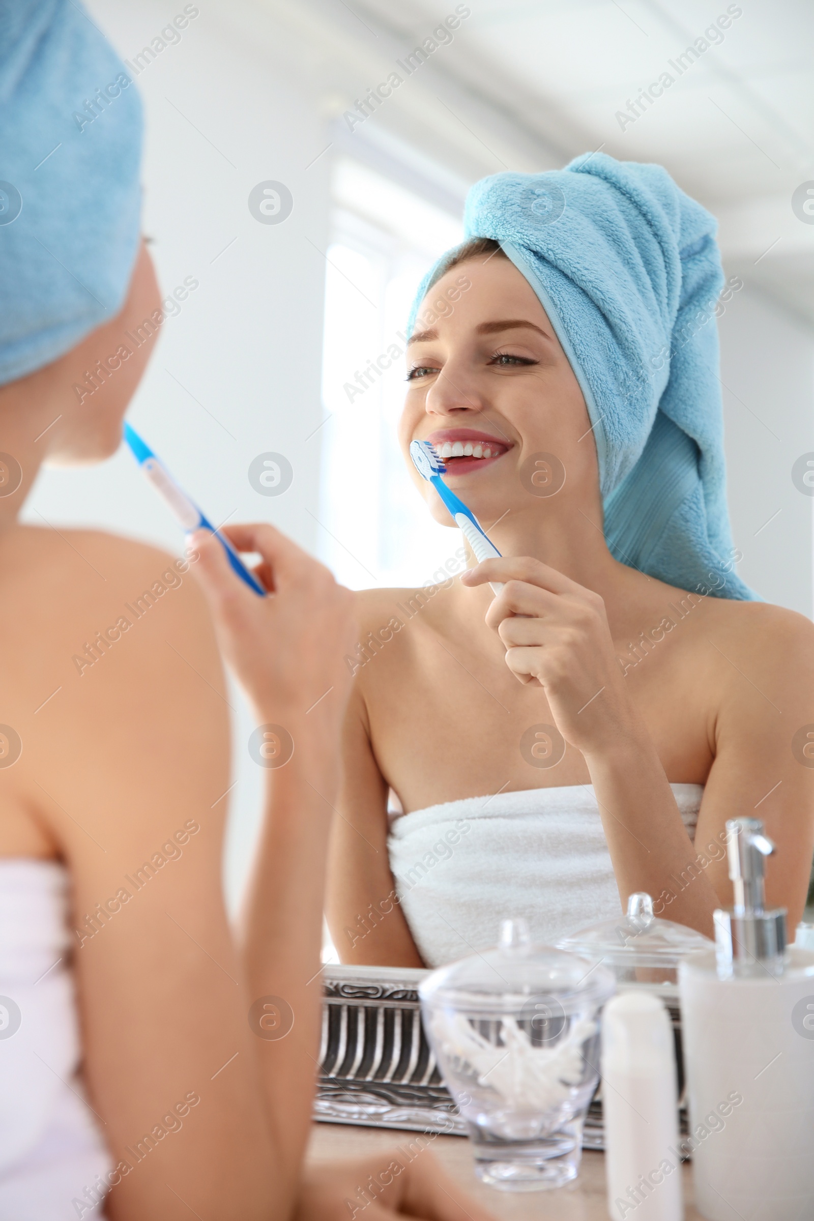 Photo of Young beautiful woman with toothbrush near mirror in bathroom. Personal hygiene