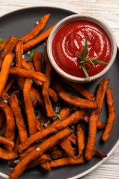 Photo of Delicious sweet potato fries served with sauce on table, top view