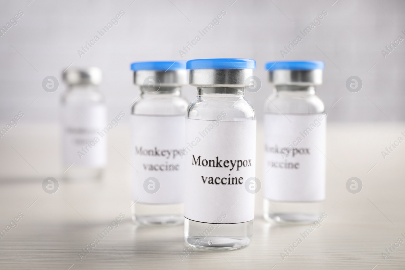 Photo of Monkeypox vaccine in glass vials on white wooden table