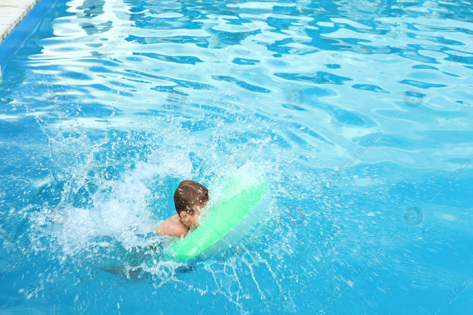 Photo of Little child with inflatable ring in outdoor swimming pool. Dangerous situation