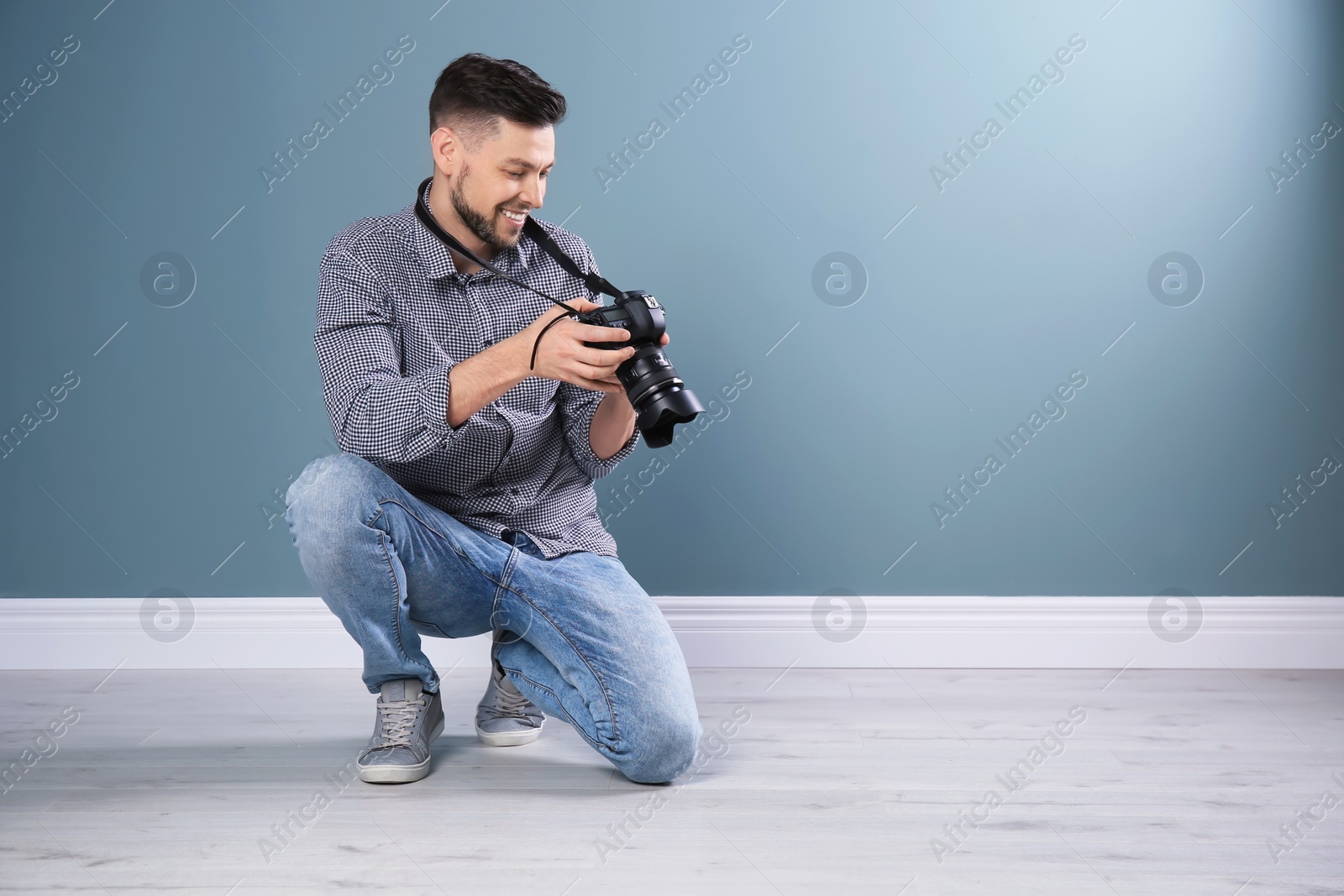 Photo of Male photographer with camera near grey wall