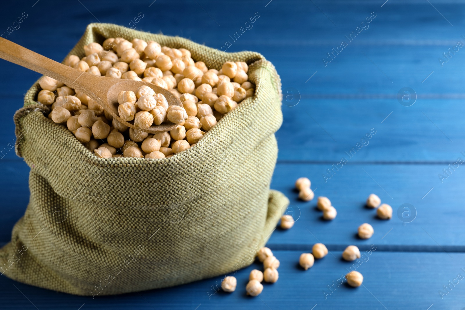 Photo of Raw chickpeas on blue wooden table, closeup