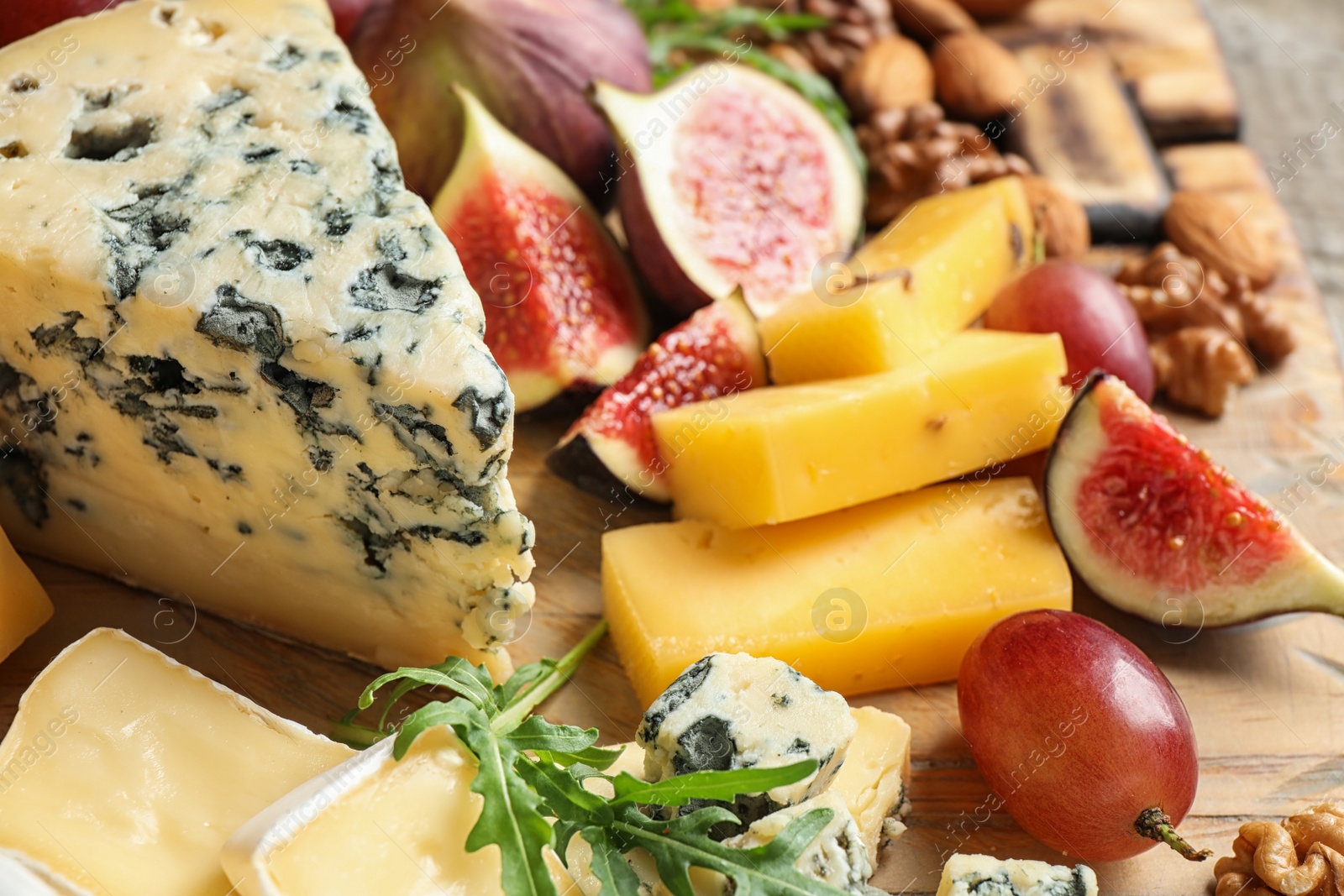 Photo of Set of different snacks with ripe figs served on wooden table, closeup