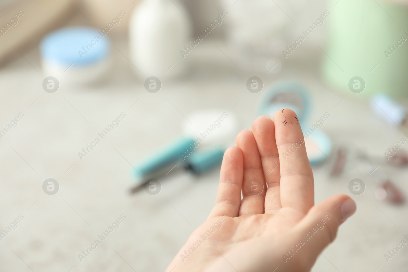 Photo of Young woman holding fallen eyelashes over table