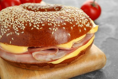 Photo of Delicious bagel with ham and cheese on grey table, closeup