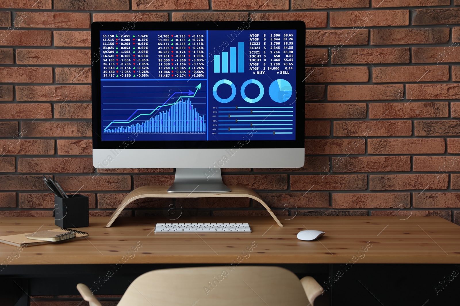 Photo of Modern computer with statistic information on wooden table near brick wall