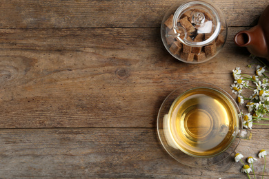 Photo of Flat lay composition with tea and chamomile flowers on wooden table. Space for text