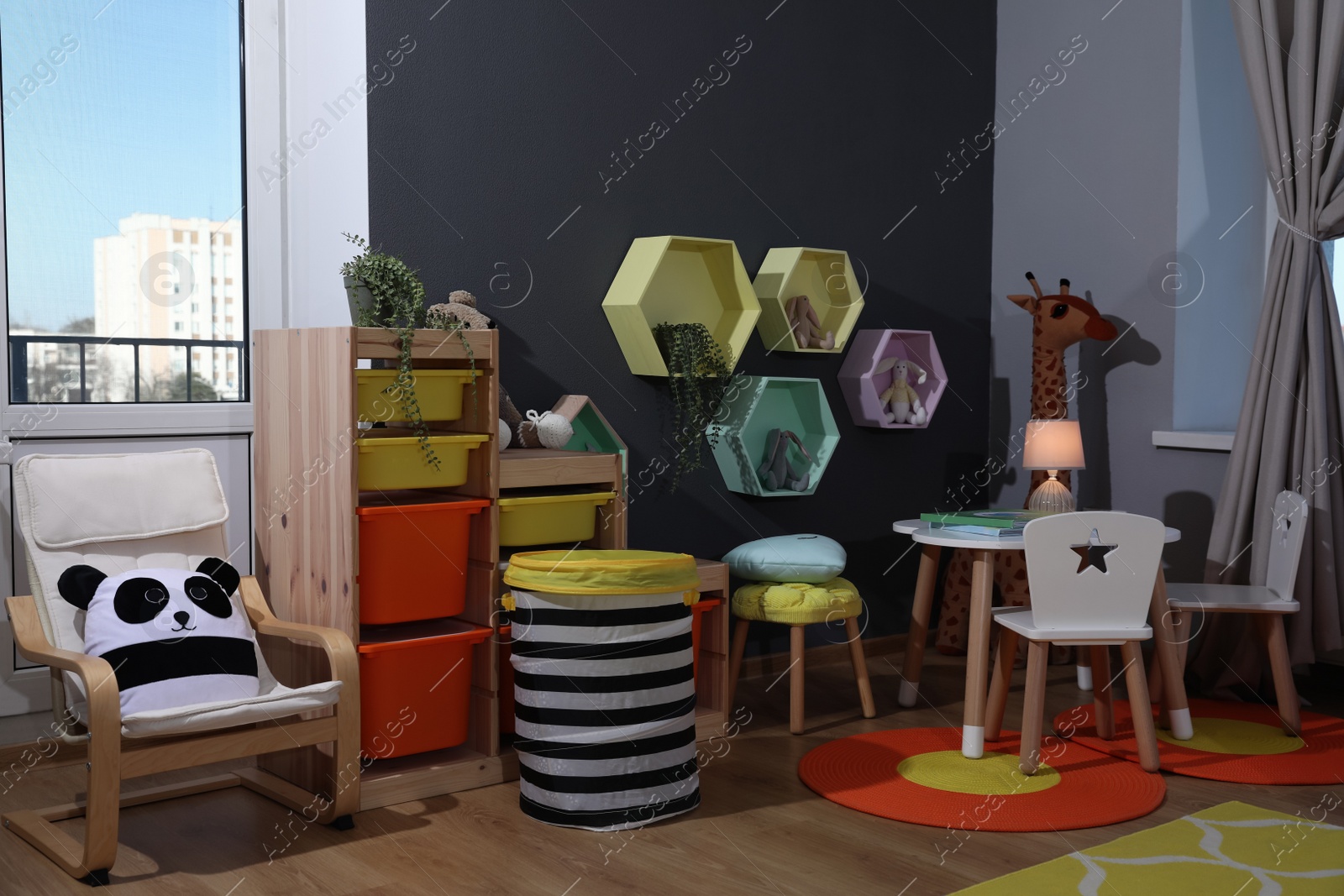 Photo of Stylish child room interior with modern furniture, toys and hexagon shaped shelves