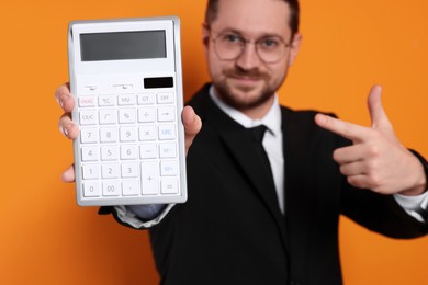 Photo of Happy accountant with calculator on orange background, selective focus