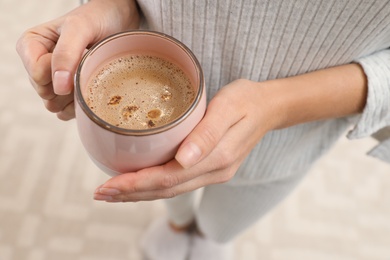 Photo of Woman holding cup of coffee indoors, closeup