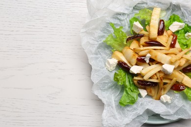 Delicious parsnip with lettuce, feta cheese and dates on white wooden table, top view. Space for text