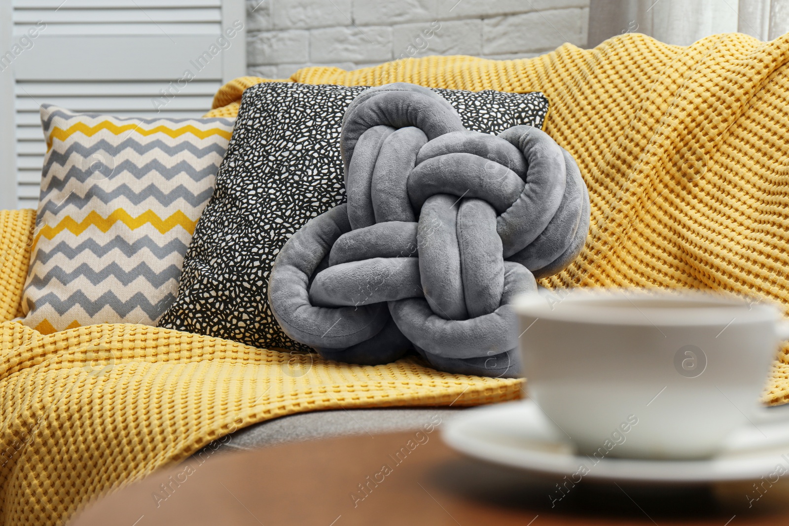 Photo of Soft pillows and yellow plaid on sofa in living room