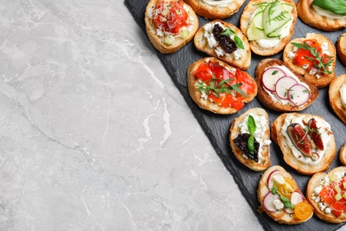 Photo of Different bruschettas on light grey marble table, top view. Space for text