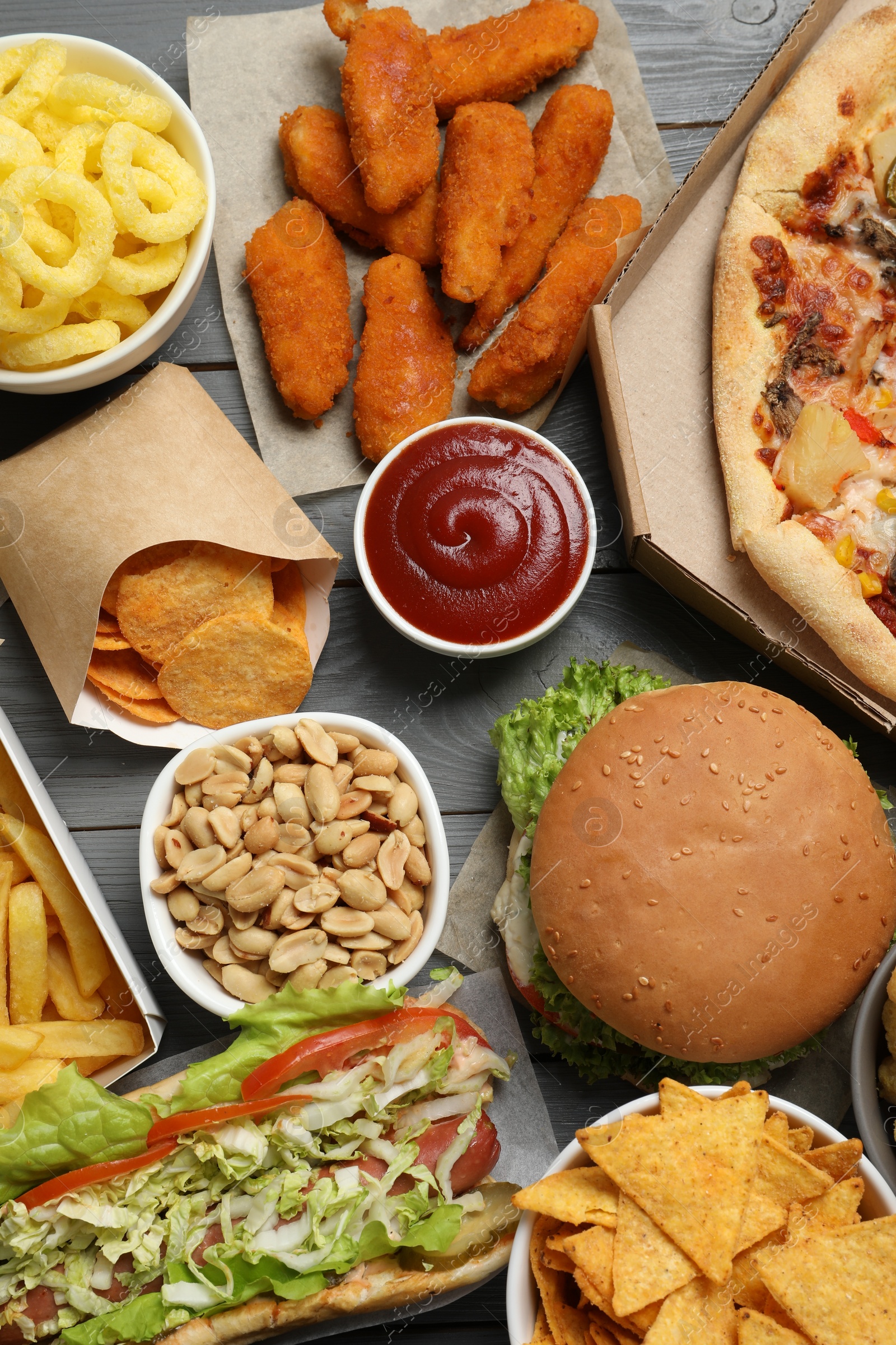 Photo of French fries, chips other fast food on gray wooden table, flat lay