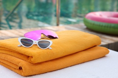 Beach towels and sunglasses on sun lounger near outdoor swimming pool. Luxury resort