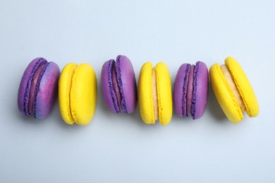 Photo of Delicious colorful macarons on light grey background, flat lay