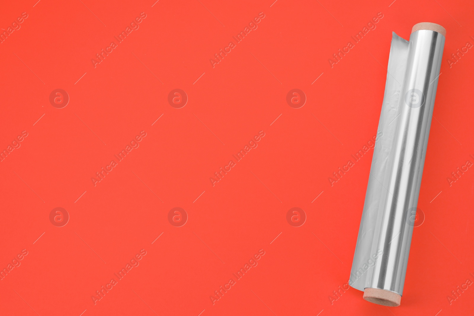Photo of Roll of aluminum foil on orange background, top view. Space for text