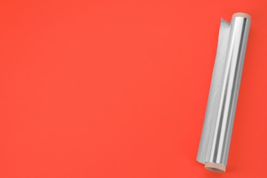 Photo of Roll of aluminum foil on orange background, top view. Space for text