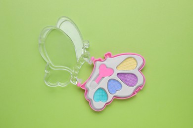 Decorative cosmetics for kids. Eye shadow palette on light green background, top view