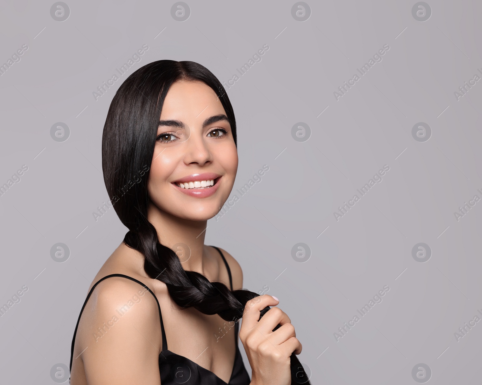 Photo of Portrait of beautiful young woman with healthy strong hair on light grey background, space for text