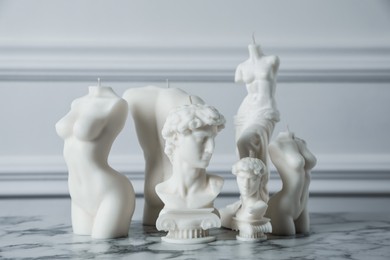 Collection of beautiful sculptural candles on white marble table. Stylish decor