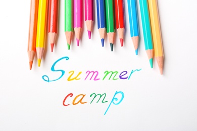 Photo of Colorful pencils and words SUMMER CAMP on white background, top view