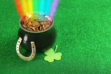 Image of Pot with gold coins, horseshoe and clover on green background, space for text. St. Patrick's Day celebration