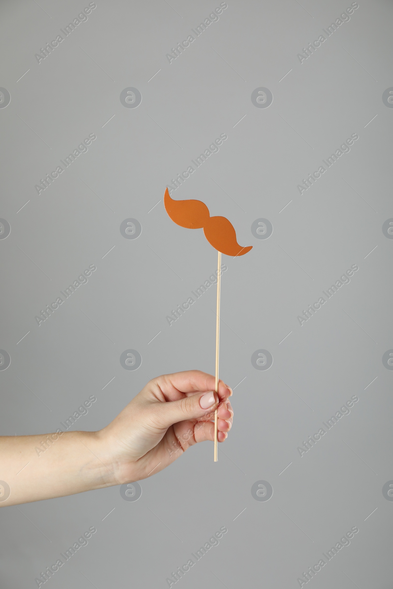 Photo of Woman with fake paper mustache on gray background, closeup