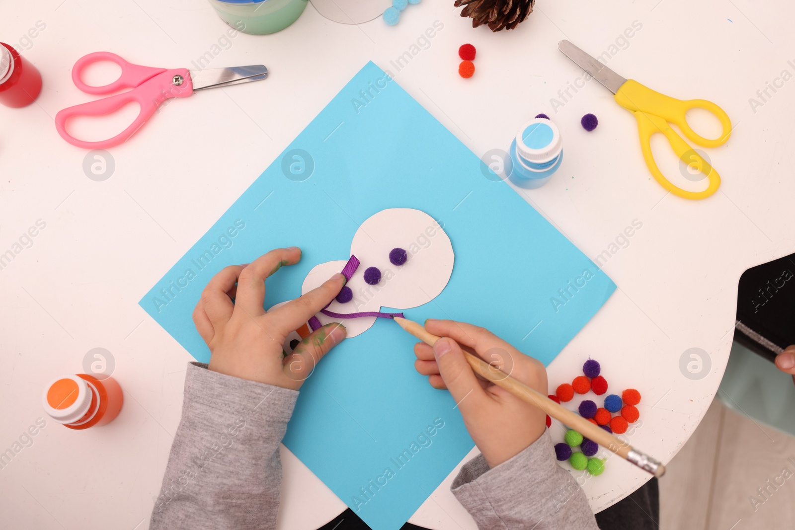 Photo of Little child making Christmas card at white table, top view