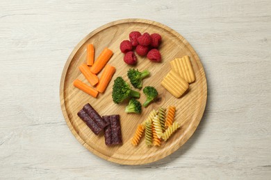 Photo of Board with different finger foods for baby on wooden table, top view