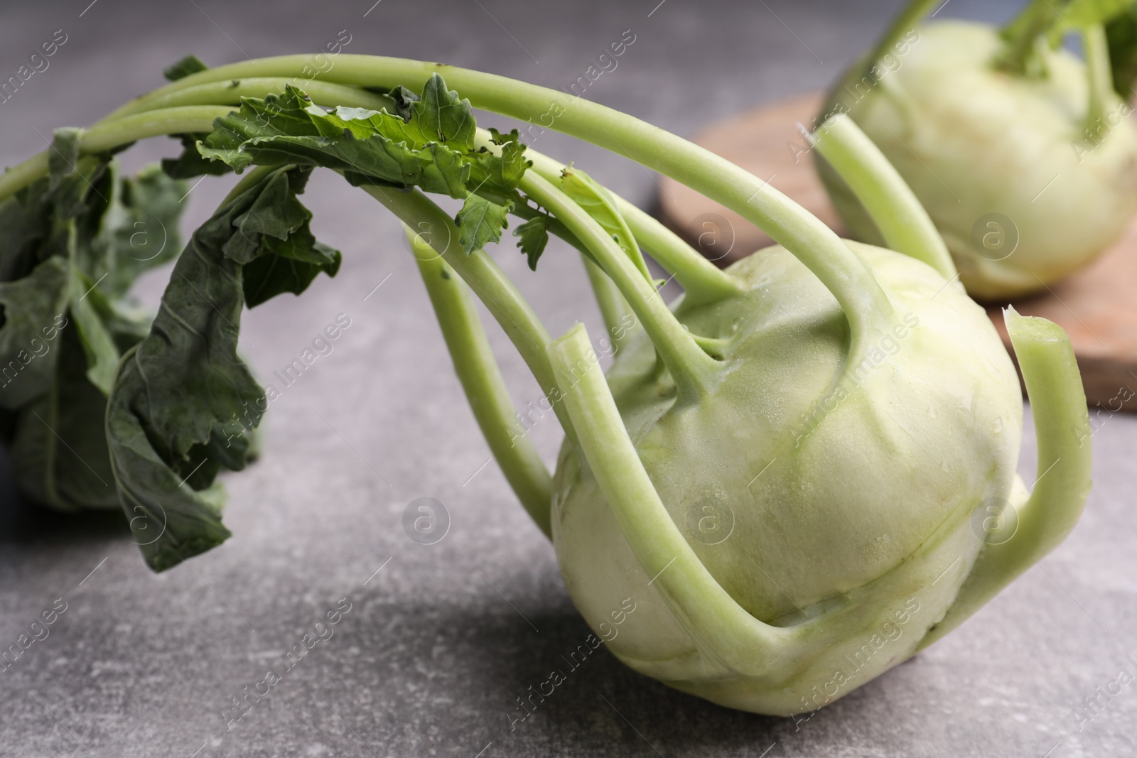 Photo of Whole ripe kohlrabi plants on grey table, closeup