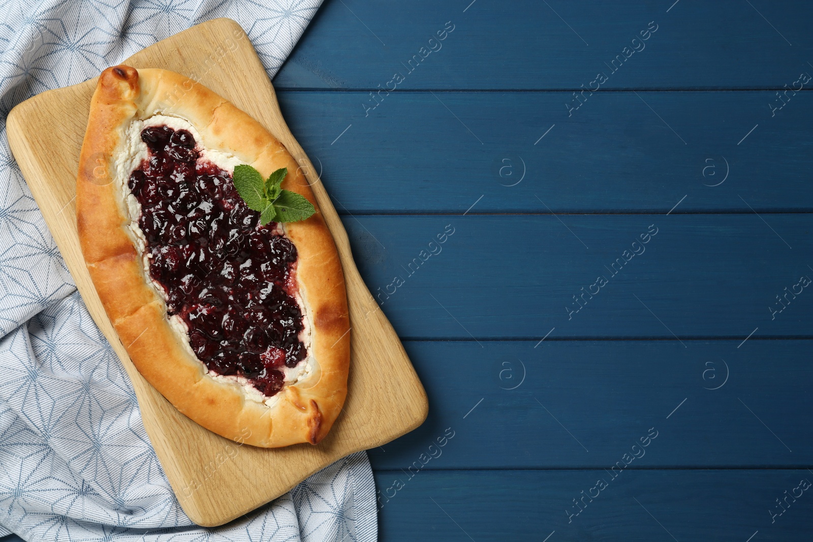 Photo of Delicious sweet cottage cheese pastry with cherry jam on blue wooden table, flat lay. Space for text