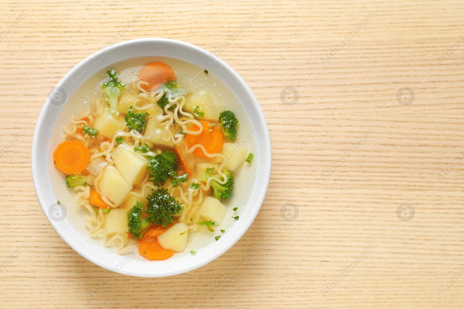 Photo of Bowl of fresh homemade vegetable soup on wooden background, top view. Space for text