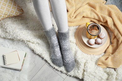 Woman and cup of hot winter drink on floor at home, above view