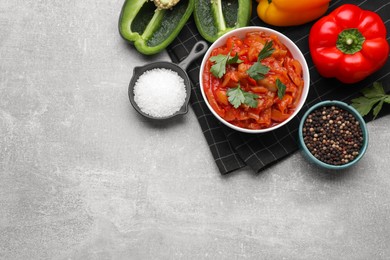 Photo of Delicious lecho in bowl and ingredients on light gray table, flat lay. Space for text